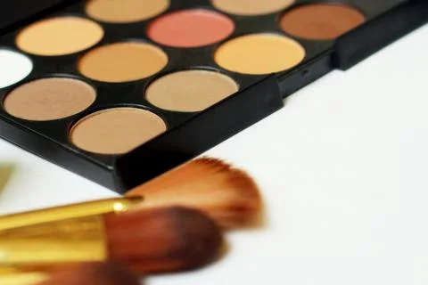 Close-up of makeup brushes, eyeshadow and powder on white background Stock Photos