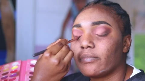Close up of makeup stylist applying makeup treatment on face of an African lady. Stock Footage 217876488