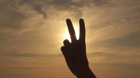 CLOSE UP: Making peace or V sign over stormy sky and golden summer sunshine Stock Footage 69103719
