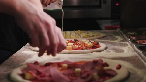 Close up of making pizza. The cook adds ingredients to three pizzas: four cheese Stock Footage 236083803
