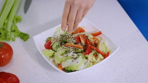 Close-up. Making a salad, a woman's hand sprinkles seeds into a vegetable salad Stock Footage 236401118