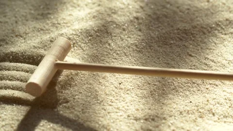 Close-up making sand zen garden using mini wooden rake with shadows and sunlight Stock Footage 265642287
