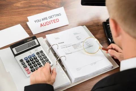 Close-up Of A Male Auditor Checking Invoice Using Magnifying Glass And Calcul Foto stock