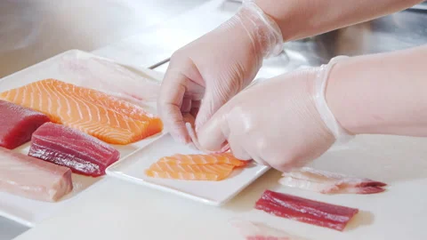 Close-up of male chef hands in gloves laying out slices of fish and octopus Stock Footage 142144591