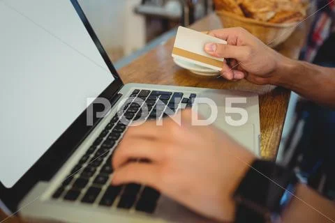 Close-Up Of Male Customer Spending Money On Online Shopping At Cafe
