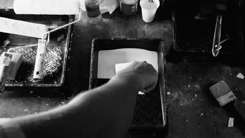 Close up male dips the roller in white paint in a black tray, back and white Stock-Footage 97350502