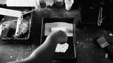 Close up male dips the roller in white paint in a black tray,black and white Stock Footage 97352599