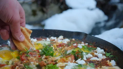 Close up of male hand dips bread in yolk and shows on background wild river Stock Footage 301365172