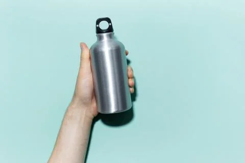 Close-up of male hand holding eco, reusable aluminum thermo water bottle. Stock Photos