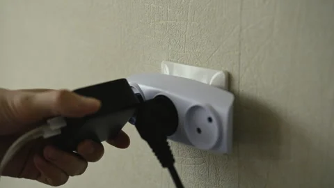 Close-up of male hand inserting black power plug into white tee outlet attached Stock Footage 311736006