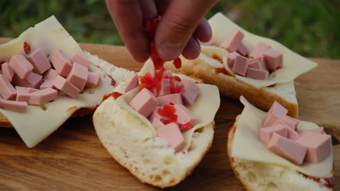 Close up of male hand put red peppers on sandwich with sausage and cheese Stock Footage 274130278