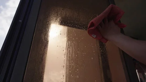 Close-up of male hand spraying window cleaner and using microfiber towel to wipe Stock Footage 313227003