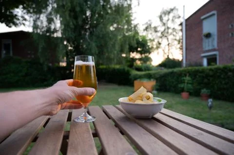 Close up of a male hand taking a glass of beer from wood table in a garden on Stock Photos