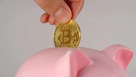 CLOSE UP: Male hand throws bitcoin into a pink piggy moneybox Stock Footage 93977102