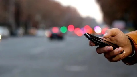 Close-up of male hand using cell phone near highway. Bokeh of car headlights Stock Footage 84975854