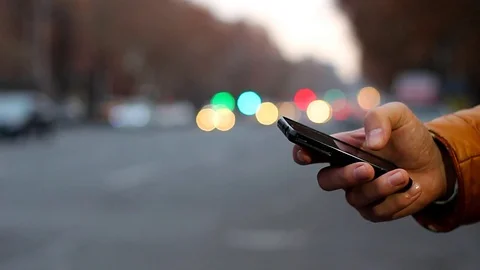 Close-up of male hand using cell phone near highway. Vidéo 84976997