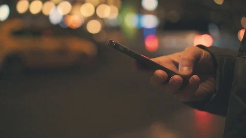 Close up of male hand using cellphone near highway. Bokeh of traffic lights Stockbeeldmateriaal 72632885