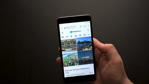 Close up male hand using smartphone scrolling through Tripadvisor Stock Footage 128310710