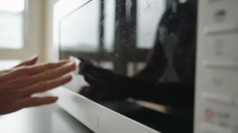 Close-up of male hand using white cleaning wipe to clean glass door of microwave Stock Footage 311054214
