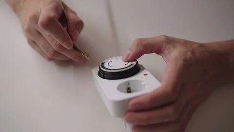 Close-up of male hands adjusting timer switch with fork, demonstrating potential Stock Footage 317398590