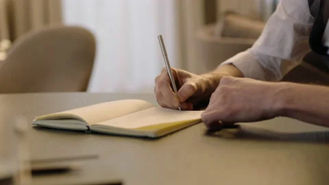 Close-up of male hands and notebook of unidentified young writer. Stockbeeldmateriaal 236772672