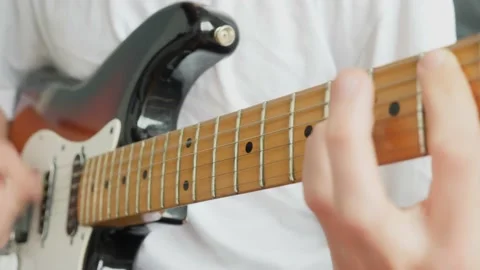 Close-up male hands clamp the strings on the fretboard of an electric guitar Stock Footage 194390725