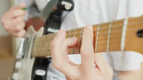 Close-up male hands clamp the strings on the fretboard of an electric guitar Stock Footage 194558580