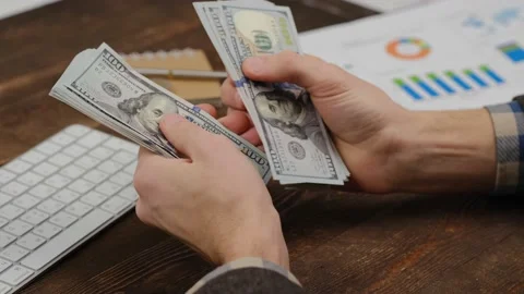 Close-up of male hands counting a stack of hundred-dollar US banknotes. Stock Footage 229427900