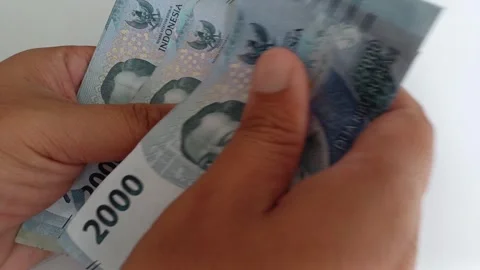 Close-up of male hands counting a stack of two thousand rupiah banknotes Stock Footage 249255658