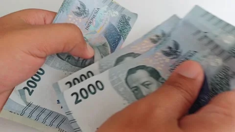 Close-up of male hands counting a stack of two thousand rupiah banknotes Stock Footage 249256068