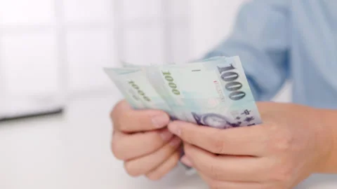 Close-up of male hands counting a stack of hundred-dollar Taiwan banknotes.New T Stock Footage 255636885
