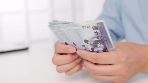 Close-up of male hands counting a stack of hundred-dollar Taiwan banknotes.New T Stock Footage 255636886