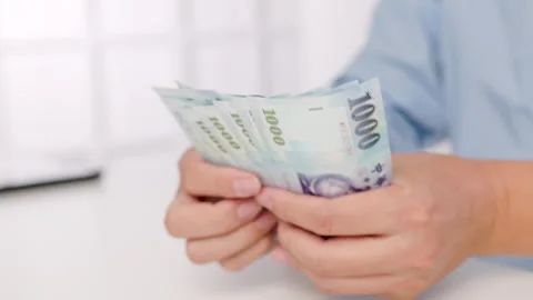 Close-up of male hands counting a stack of hundred-dollar Taiwan banknotes.New T Stock Footage 255637029