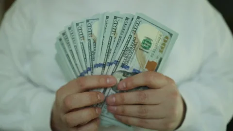 Close-up of male hands counting a stack of hundred-dollar US banknotes. a Stock Footage 304823376