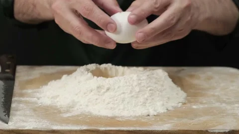 Close up of male hands cracking eggs upon flour Video stock 198735312