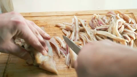 Close-up. male hands cut into strips boiled pork ears on wooden cutting board Stock Footage 148471072