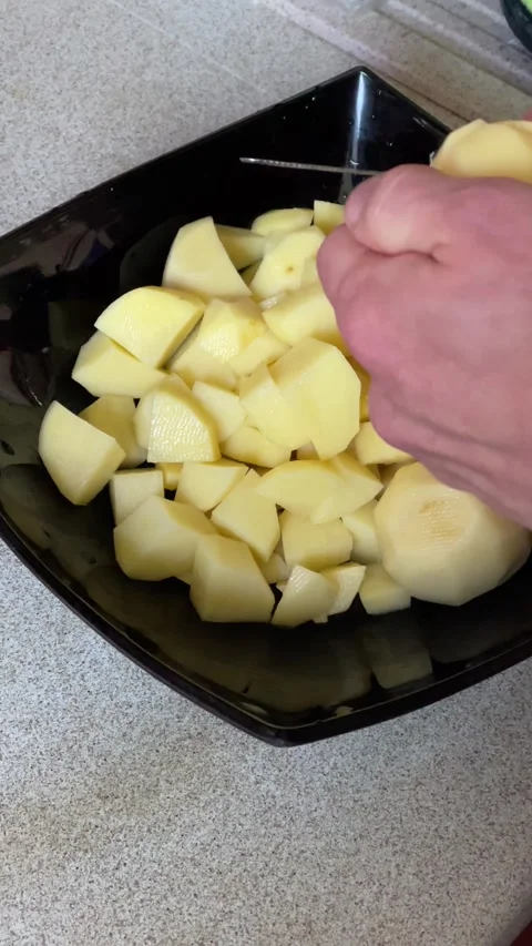 Close up of male hands cutting raw potatoes into a bowl Stock Footage 272157789