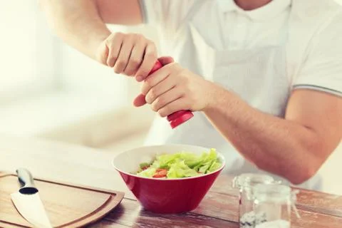 Close up of male hands flavouring salad in a bowl Stock Photos