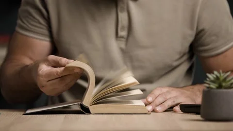 Close Up of Male Hands Flipping Through Book Pages on Wooden Desk Stock Footage 342236615