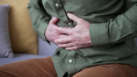Close-up of male hands holding and massaging stomach while sitting on sofa  Stock Footage 328706294