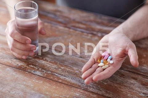 Close Up Of Male Hands Holding Pills And Water