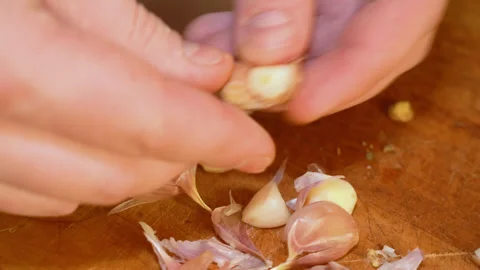 Close-up of male hands at home kitchen clean garlic from the peel Stock Footage 247833562