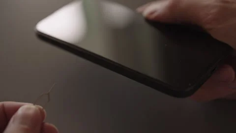 Close-up of male hands inserting sim ejector tool into smartphone to remove or Stock Footage 321403965