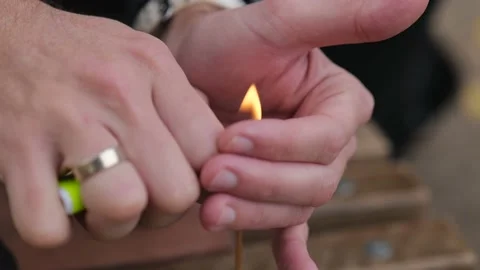 Close-up of male hands lighting an incense stick with a lighter Stock Footage 229860405