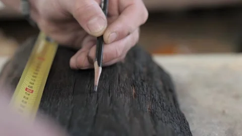 Close-up of male hands making markings on a burnt wooden board with a simple  Stock Footage 140323016