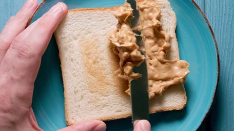 CLOSE UP: Male hands making a peanut butter sandwich. Top view. Stock Footage 142048629