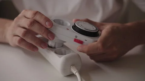 Close-up of male hands plugging mechanical timer switch into extension cord Stock Footage 317541563