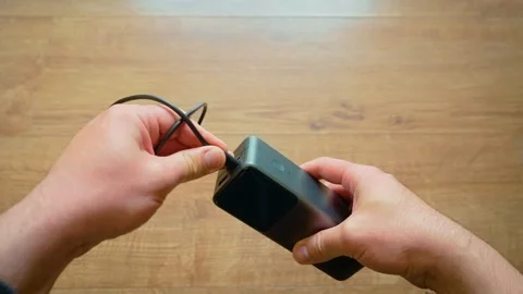 Close up male hands pulling USB cable from power bank portable charger modern Stock Footage 336969728