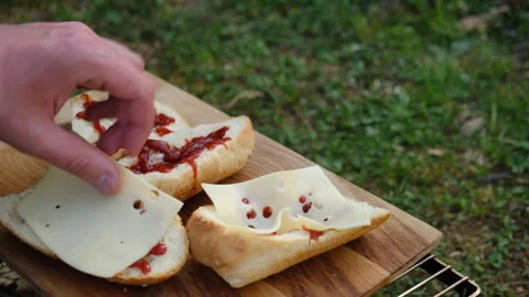 Close up of male hands putting cheese on baguette with tomato sauce in nature Stock Footage 274132653