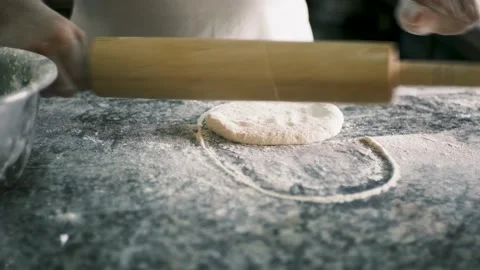 Close-up male hands roll out pastry with wooden rolling pin on a stone table Stock Footage 199214580